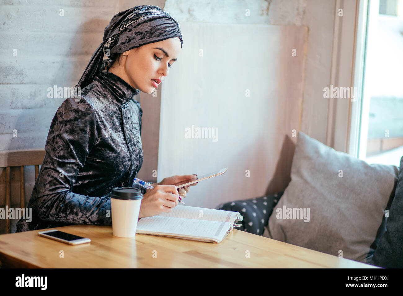 Arabian Businesswoman working in coffee shop with digital tablet and drink coffee Stock Photo