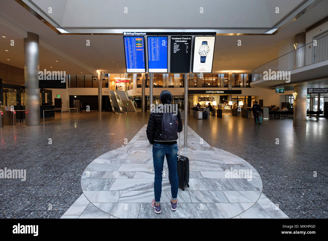 Female traveler walking through Zurich Airport with a rolling suitcase, Zurich, Switzerland, Europe Stock Photo