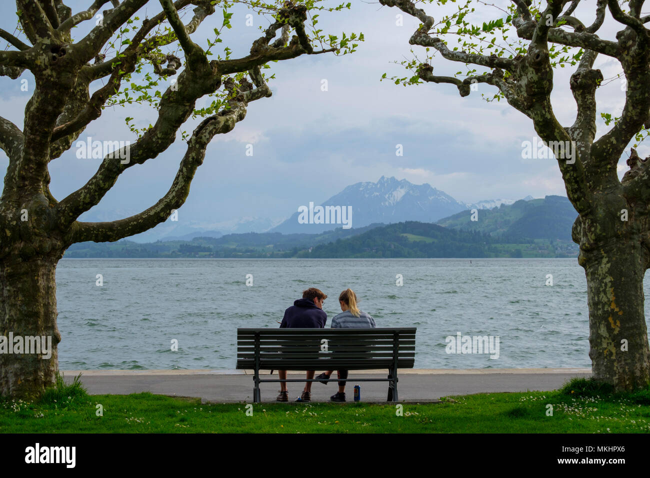 Man and woman sitting in a park bench in front of the lake in Zug, Switzerland, Europe Stock Photo