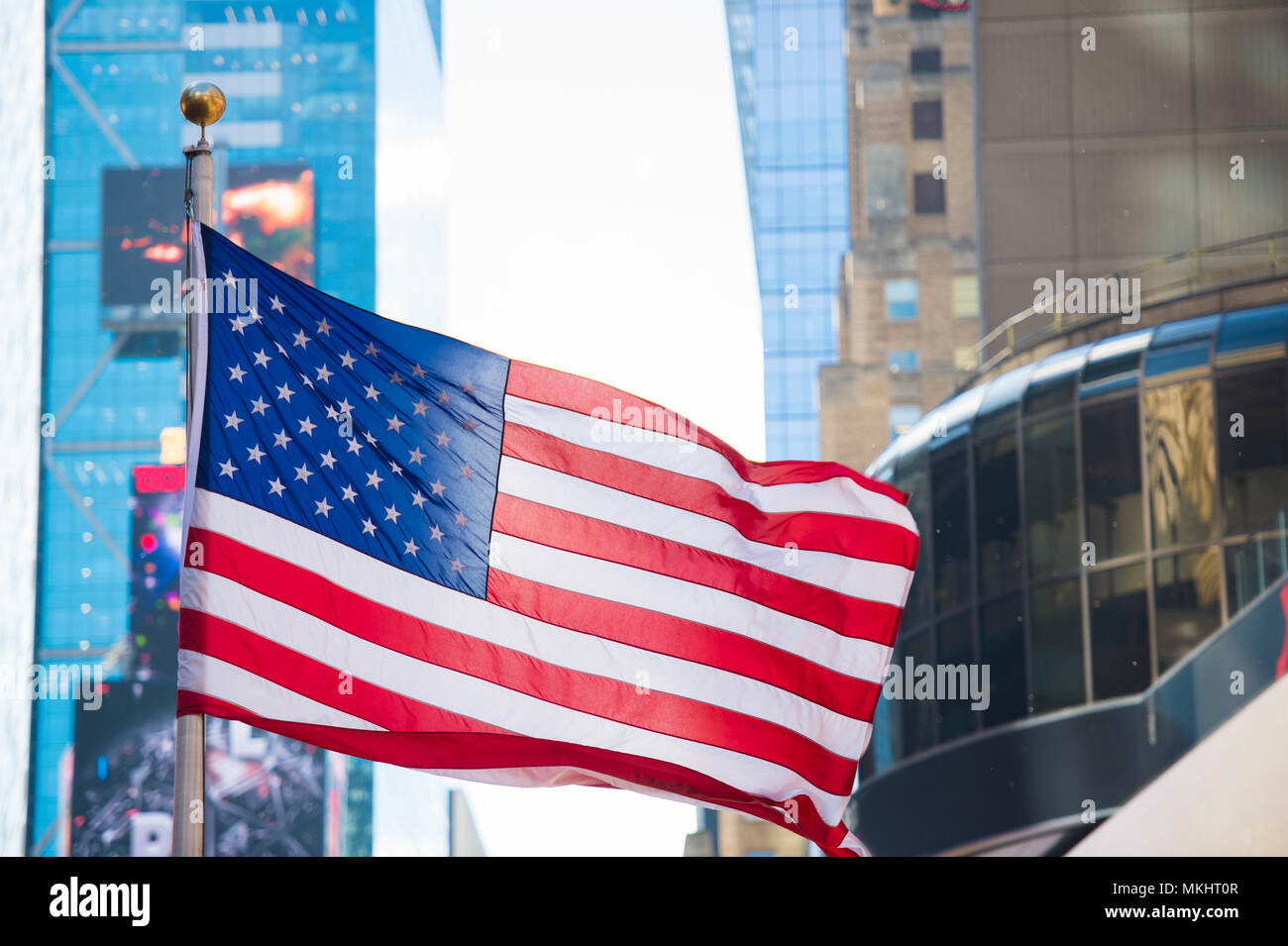 Close-up view of an American flag waving in Times Square in Manhattan. Blurred skyscrapers in the background. New York City, USA. Stock Photo