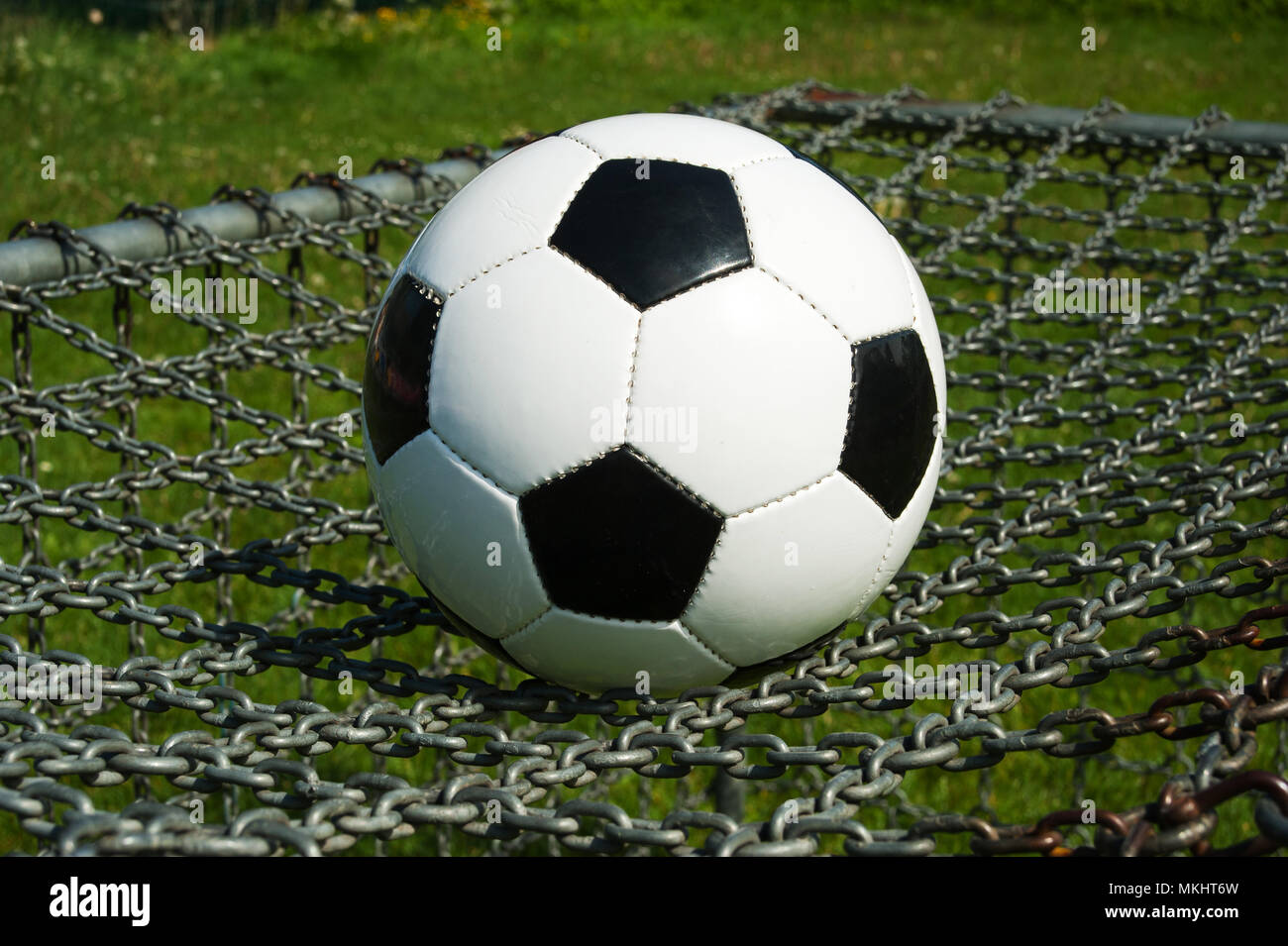 soccer ball classic black and white on the top of a chain goal in the summer outdoor Stock Photo