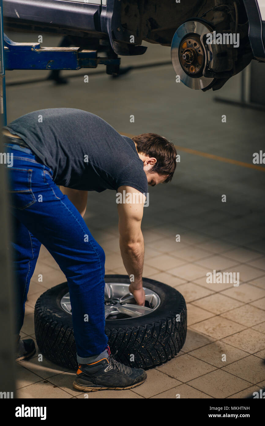 Auto mechanic changing wheels tires Inside garage Stock Photo