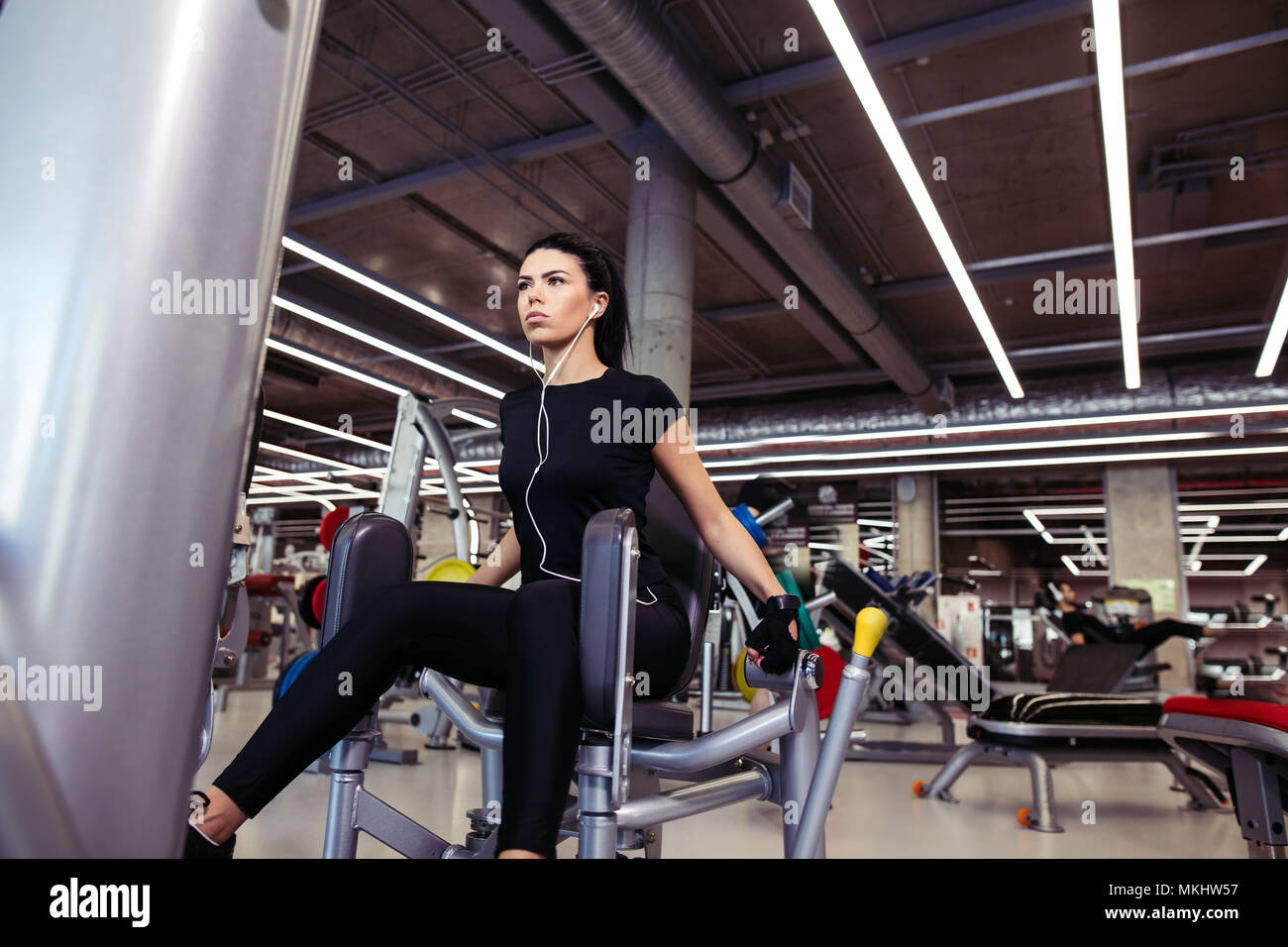 Adduction or abductor machine. fit girl exercising her legs in gym Stock Photo