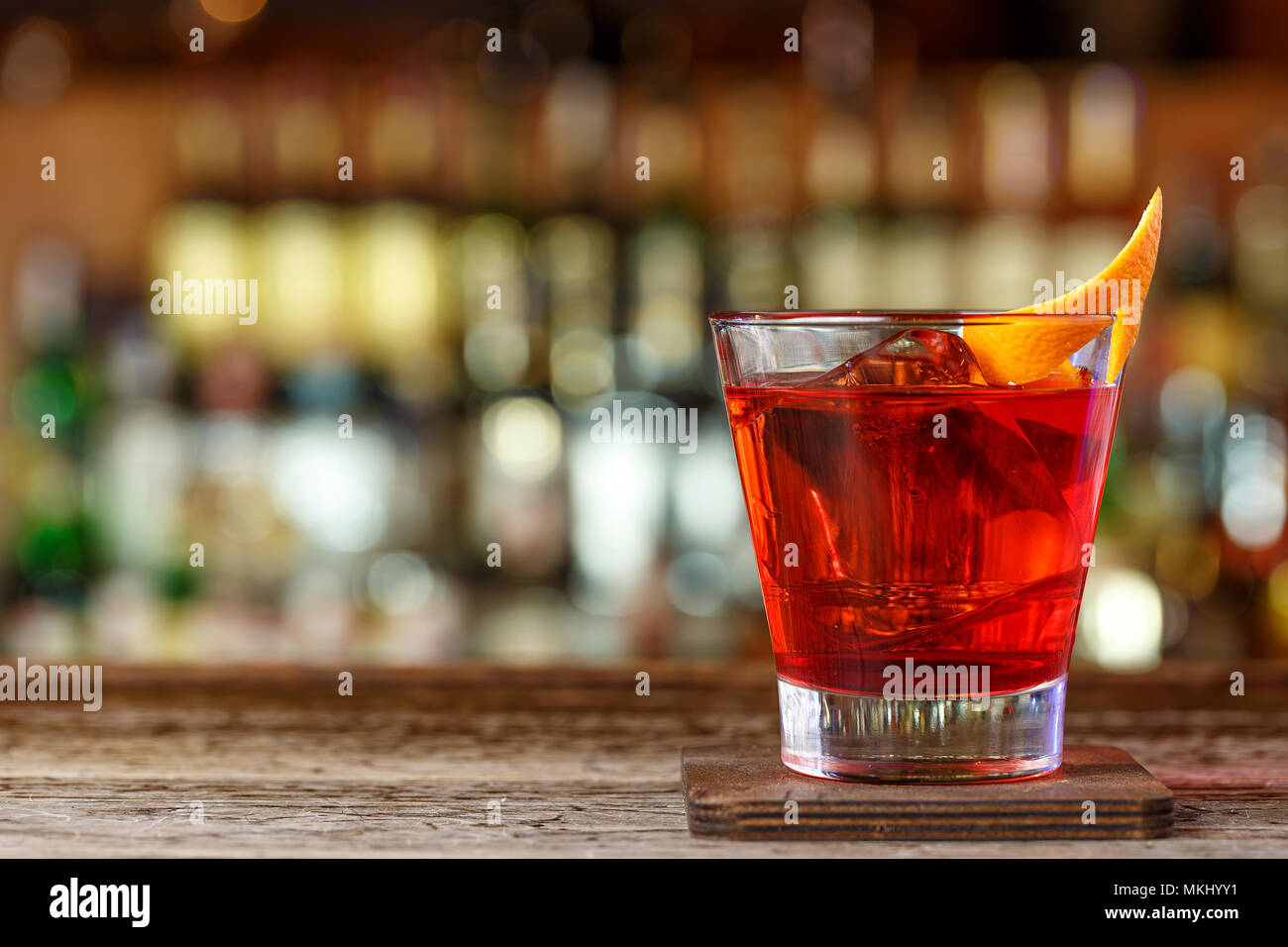 Cocktail Negroni in a nightclub on a shabby wooden bar counter. Cocktail with gin, campari and martini rosso Stock Photo