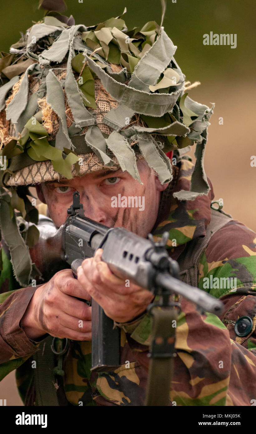 1970 – 1980 British Army soldier in camouflage suit and steel helmet carrying a SLR (Self-Loading Rifle) L1A1 - calibre of 7.62 mm (Posed by Model) Stock Photo
