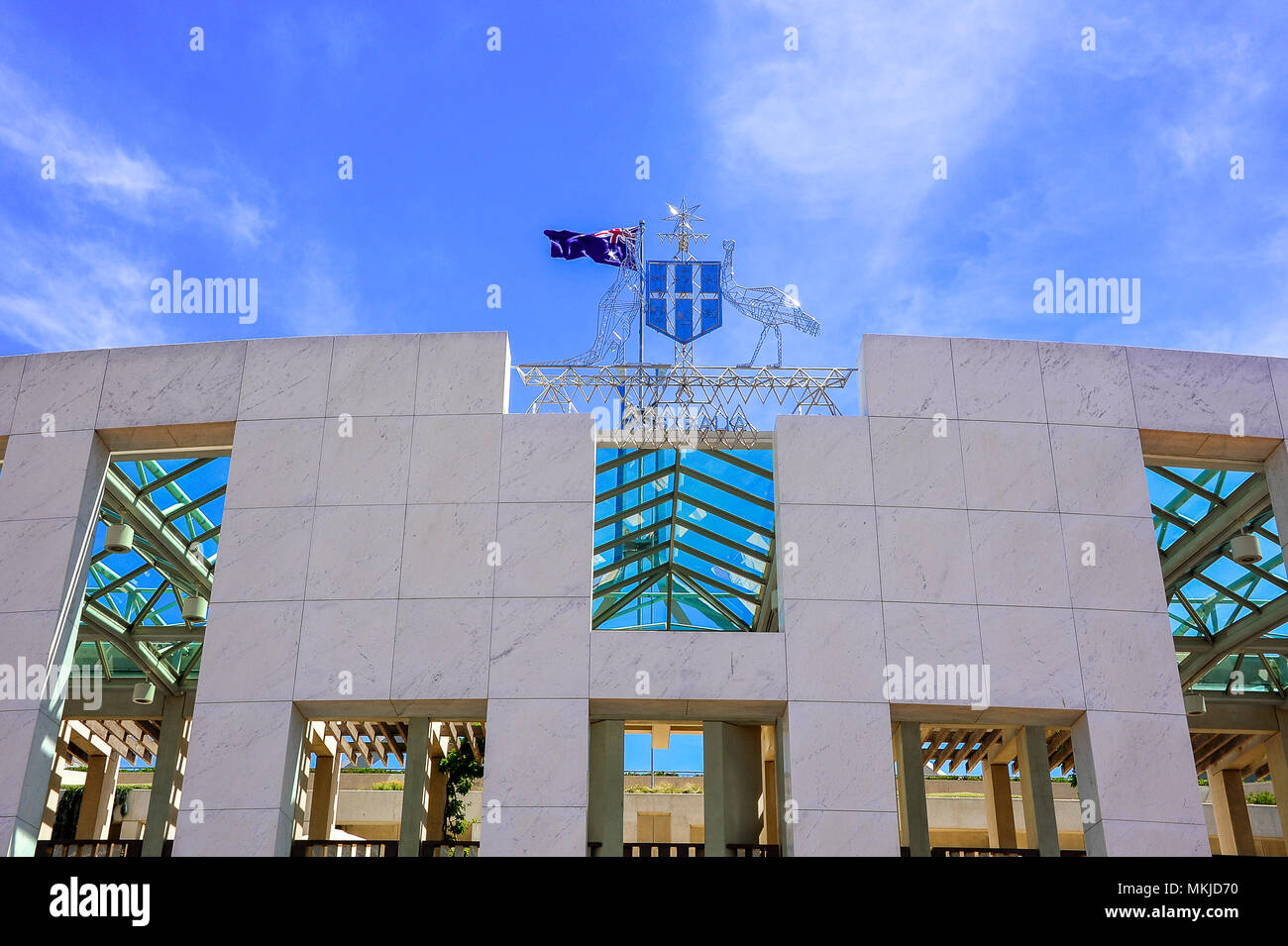 Main entrance to New Parliament House, with the coat of arms displaying the kangaroo, emu and Commonwealth star against a deep blue sky Stock Photo