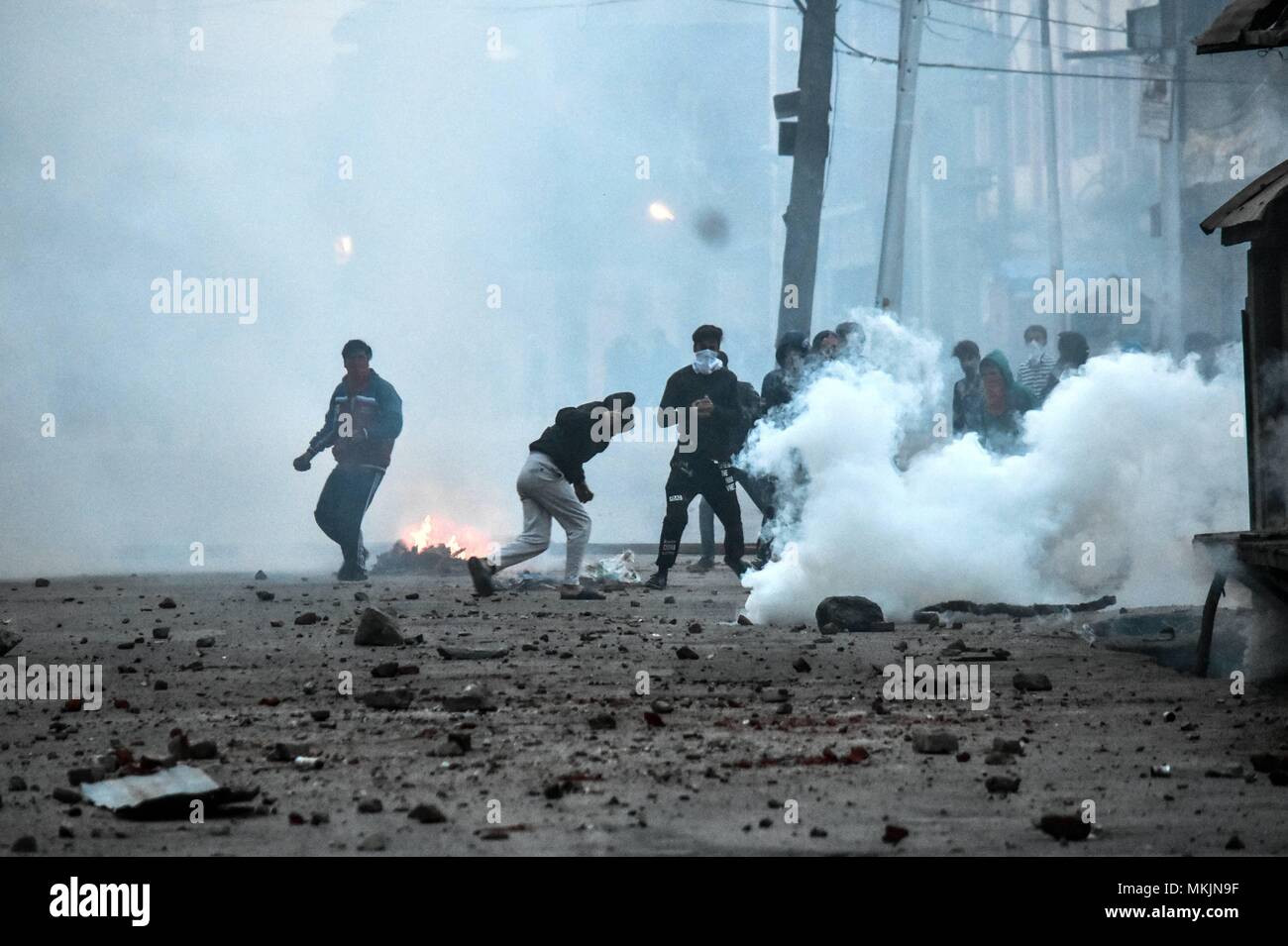 Srinagar, Kashmir. 8th May 2018. Kashmiri protesters throw stones amid tear smoke during clashes with government forces in Srinagar, Kashmir. Fierce clashes broke out between government forces and Kashmiri protesters in Srinagar on Tuesday as the valley continued to remain tense over the killing of 11 people including 5 militants and 6 civilians in Kashmir. Police used tear smoke shells and shot gun pellets to disperse hundreds of demonstrators who hurled rocks and chanted anti-and pro-freedom slogans. Credit: SOPA Images Limited/Alamy Live News Stock Photo