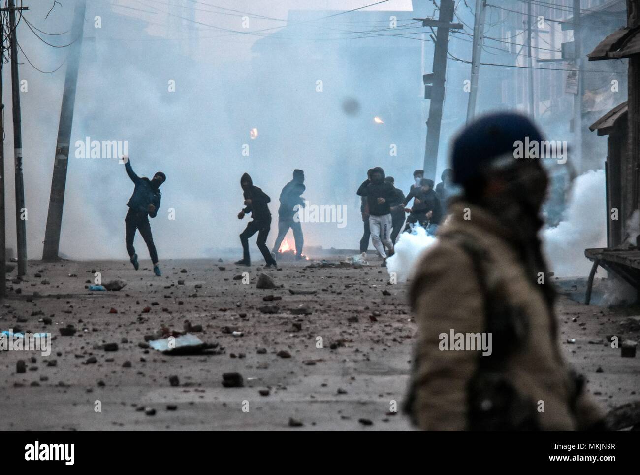 Srinagar, Kashmir. 8th May 2018. Kashmiri protesters throw stones amid tear smoke during clashes with government forces in Srinagar, Kashmir. Fierce clashes broke out between government forces and Kashmiri protesters in Srinagar on Tuesday as the valley continued to remain tense over the killing of 11 people including 5 militants and 6 civilians in Kashmir. Police used tear smoke shells and shot gun pellets to disperse hundreds of demonstrators who hurled rocks and chanted anti-and pro-freedom slogans. Credit: SOPA Images Limited/Alamy Live News Stock Photo