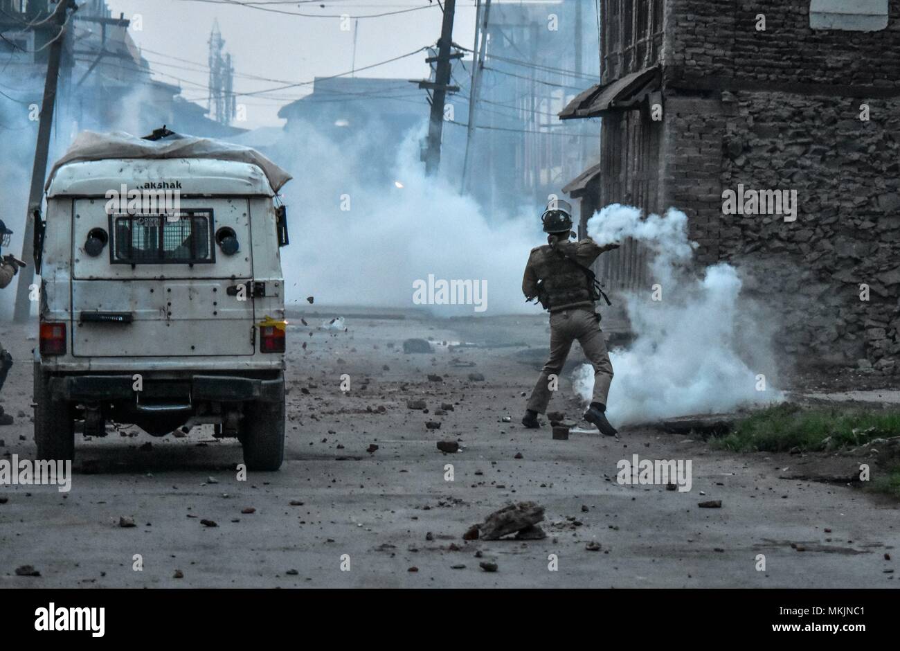 May 8, 2018 - Srinagar, J&K, India - An Indian policeman throws a tear gas canister back towards Kashmiri protesters during clashes in Srinagar, Indian administered Kashmir. Fierce clashes broke out between government forces and Kashmiri protesters in Srinagar on Tuesday as the valley continued to remain tense over the killing of 11 people including 5 militants and 6 civilians in Indian administered Kashmir. Police used tear smoke shells and shot gun pellets to disperse hundreds of demonstrators who hurled rocks and chanted anti-Indian and pro-freedom slogans. (Credit Image: © Saqib Majeed/SOP Stock Photo