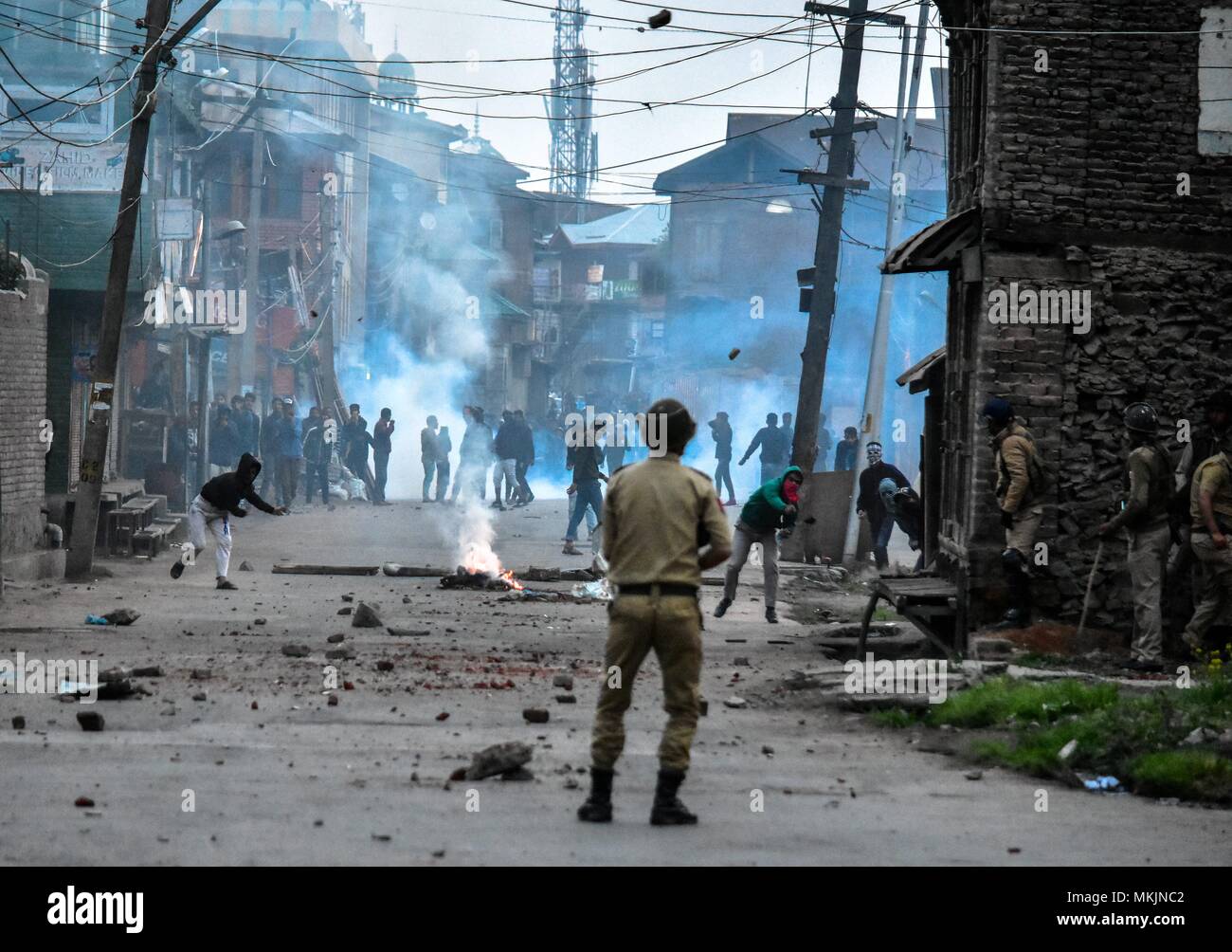 May 8, 2018 - Srinagar, J&K, India - Kashmiri protesters throw stones towards Indian policeman during clashes in Srinagar, Indian administered Kashmir. Fierce clashes broke out between government forces and Kashmiri protesters in Srinagar on Tuesday as the valley continued to remain tense over the killing of 11 people including 5 militants and 6 civilians in Indian administered Kashmir. Police used tear smoke shells and shot gun pellets to disperse hundreds of demonstrators who hurled rocks and chanted anti-Indian and pro-freedom slogans. (Credit Image: © Saqib Majeed/SOPA Images via ZUMA Wire Stock Photo
