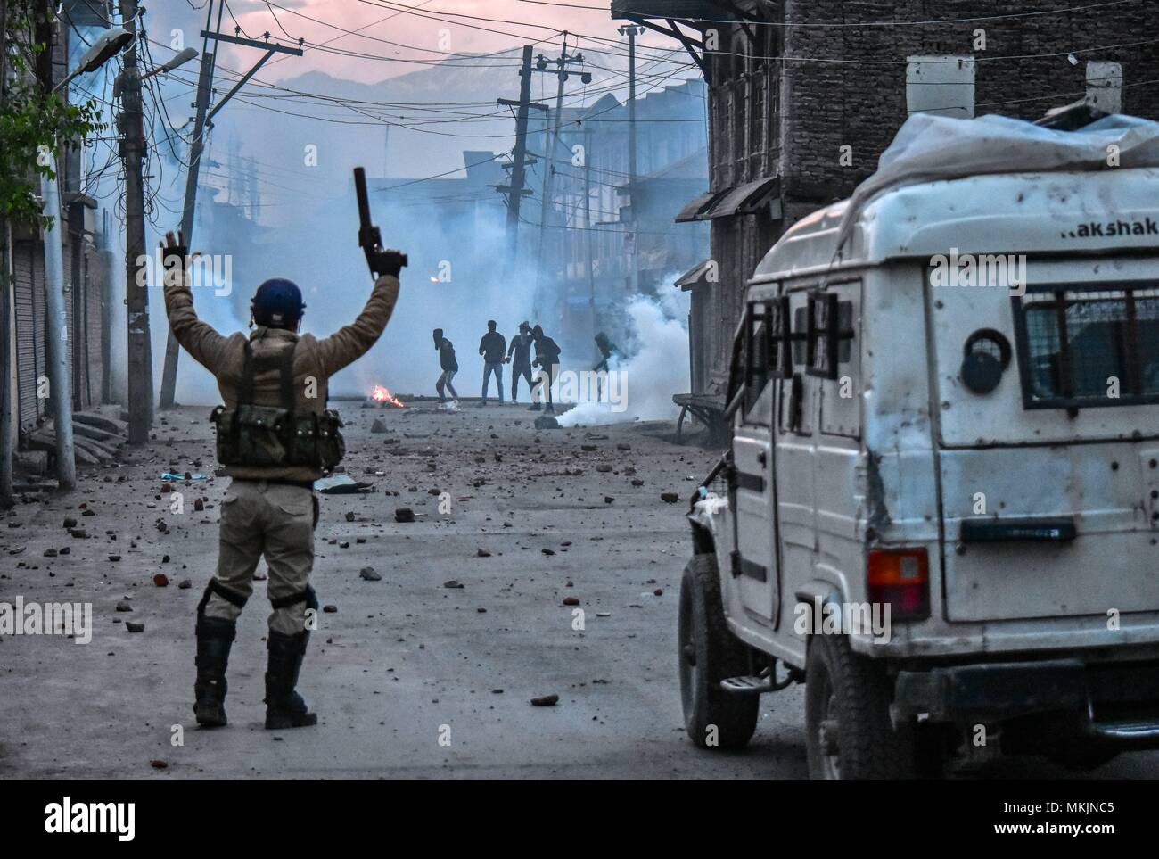 May 8, 2018 - Srinagar, J&K, India - An Indian policeman taunts Kashmiri protesters during clashes in Srinagar, Indian administered Kashmir. Fierce clashes broke out between government forces and Kashmiri protesters in Srinagar on Tuesday as the valley continued to remain tense over the killing of 11 people including 5 militants and 6 civilians in Indian administered Kashmir. Police used tear smoke shells and shot gun pellets to disperse hundreds of demonstrators who hurled rocks and chanted anti-Indian and pro-freedom slogans. Credit: Saqib Majeed/SOPA Images/ZUMA Wire/Alamy Live News Stock Photo