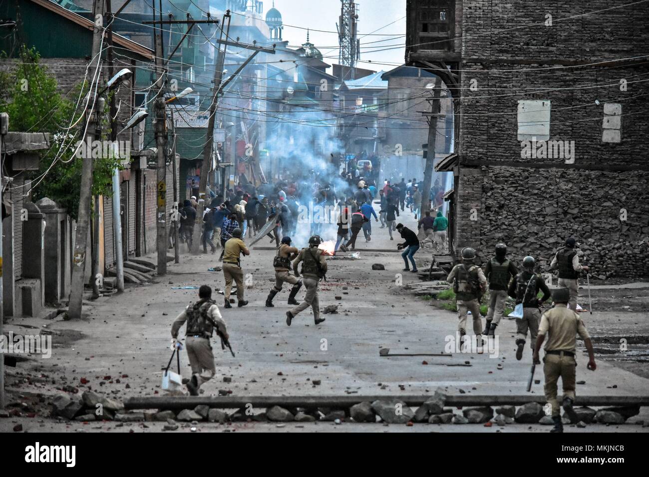 May 8, 2018 - Srinagar, J&K, India - Indian government forces chase Kashmiri protesters during clashes in Srinagar, Indian administered Kashmir. Fierce clashes broke out between government forces and Kashmiri protesters in Srinagar on Tuesday as the valley continued to remain tense over the killing of 11 people including 5 militants and 6 civilians in Indian administered Kashmir. Police used tear smoke shells and shot gun pellets to disperse hundreds of demonstrators who hurled rocks and chanted anti-Indian and pro-freedom slogans. Credit: Saqib Majeed/SOPA Images/ZUMA Wire/Alamy Live News Stock Photo
