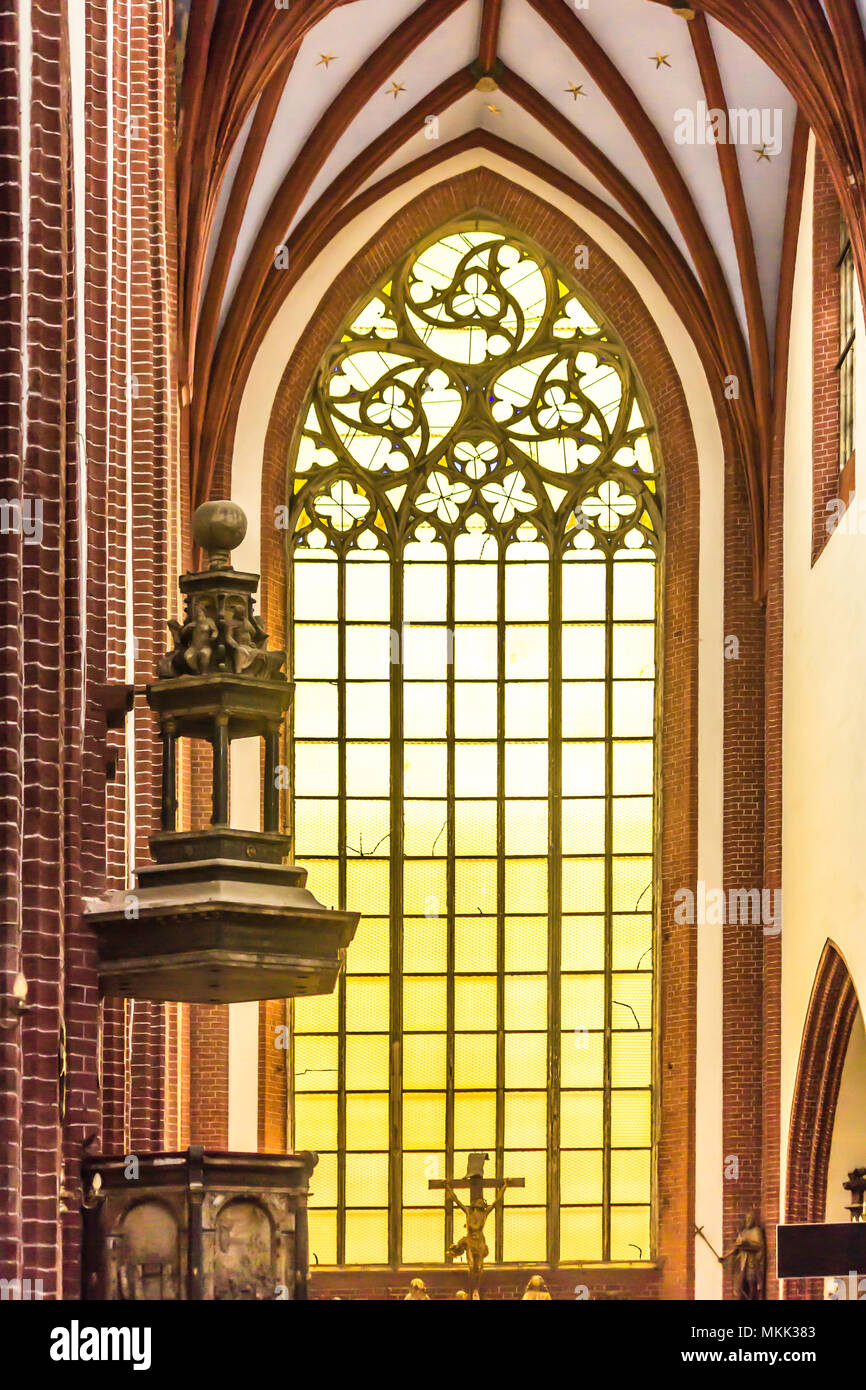 Interior of a brick cathedral in the Gothic style. A decorated anbon and a large stained glass window. St.Mary Magdalene Church. Wroclaw,Poland. Stock Photo