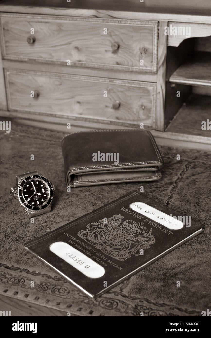 british passport, wallet and rolex watch on timber antique desk, with name blanked out Stock Photo