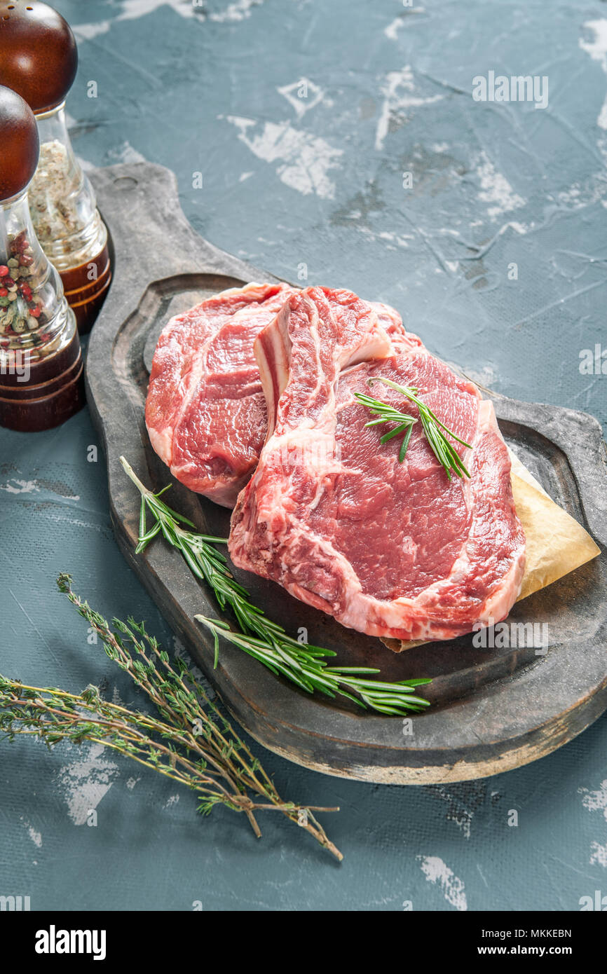 Cutting beef for grilling on a wooden cutting Board with Bay leaf, rosemary  for marinade in a rustic style. Copy space Stock Photo - Alamy