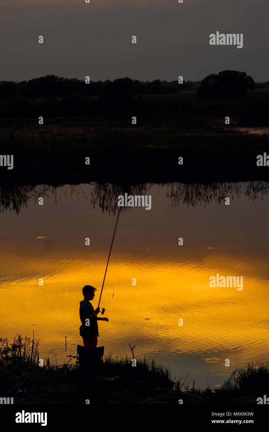 Sunset silhouette fisherman casting fishing hi-res stock