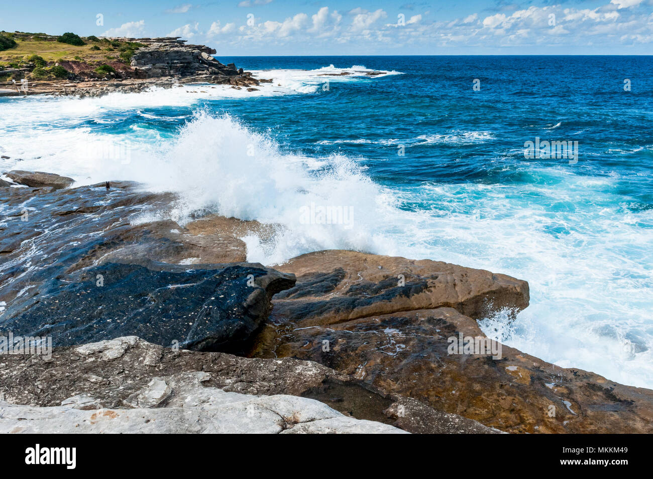 The stunning views along the famous Coogee Beach walk near to Bondi Beach, New South Wales, Australia. Waves crashing on the rocks with a beautiful bl Stock Photo