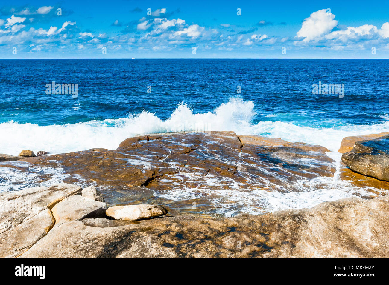 The stunning views along the famous Coogee Beach walk near to Bondi Beach, New South Wales, Australia. Waves crashing on the rocks with a beautiful bl Stock Photo