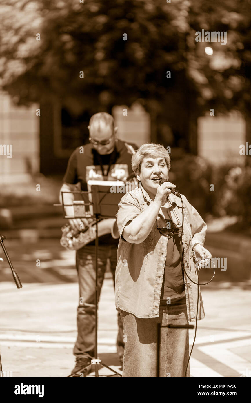 DIMITROVGRAD, BULGARIA - APRIL 30, 2018: The female singer of the jazz band sings passionately on microphone at street concert event dedicated to International World Jazz Day Stock Photo