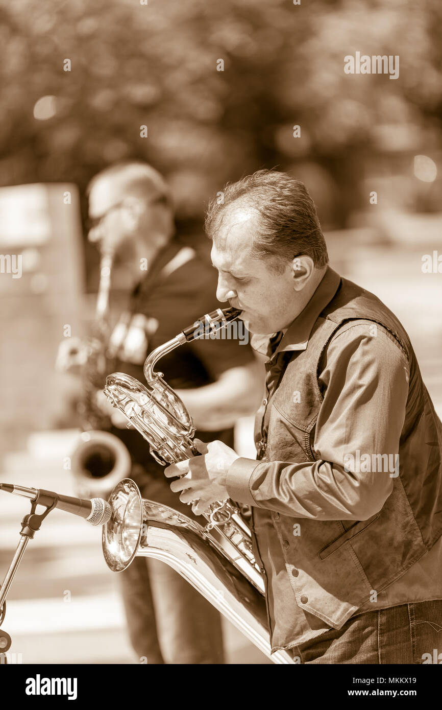 DIMITROVGRAD, BULGARIA - APRIL 30, 2018: Male sax player performs complicated music on his bass saxophone at street concert event dedicated to International World Jazz Day Stock Photo