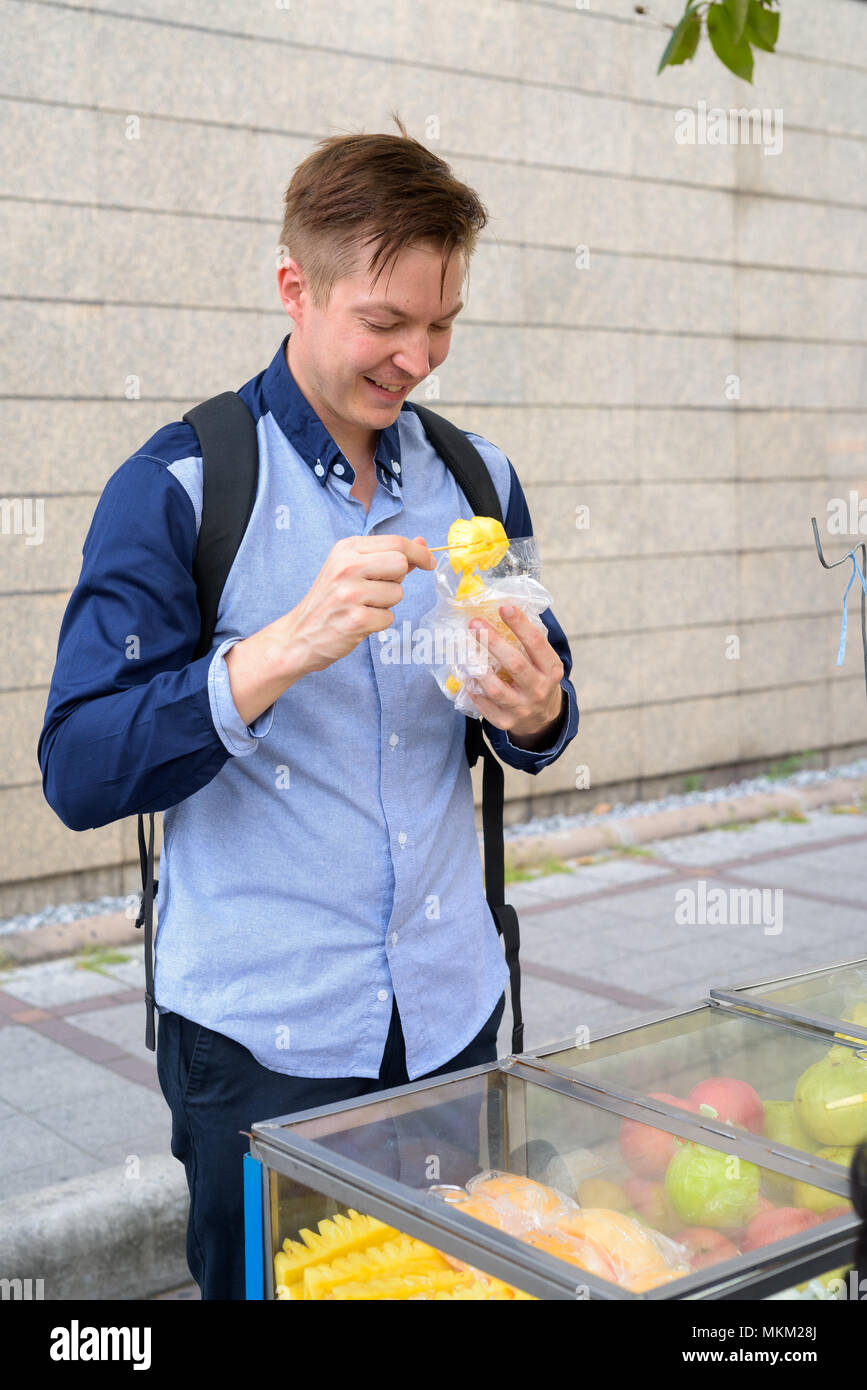 Young happy tourist man backpacker shopping at the street market Stock Photo