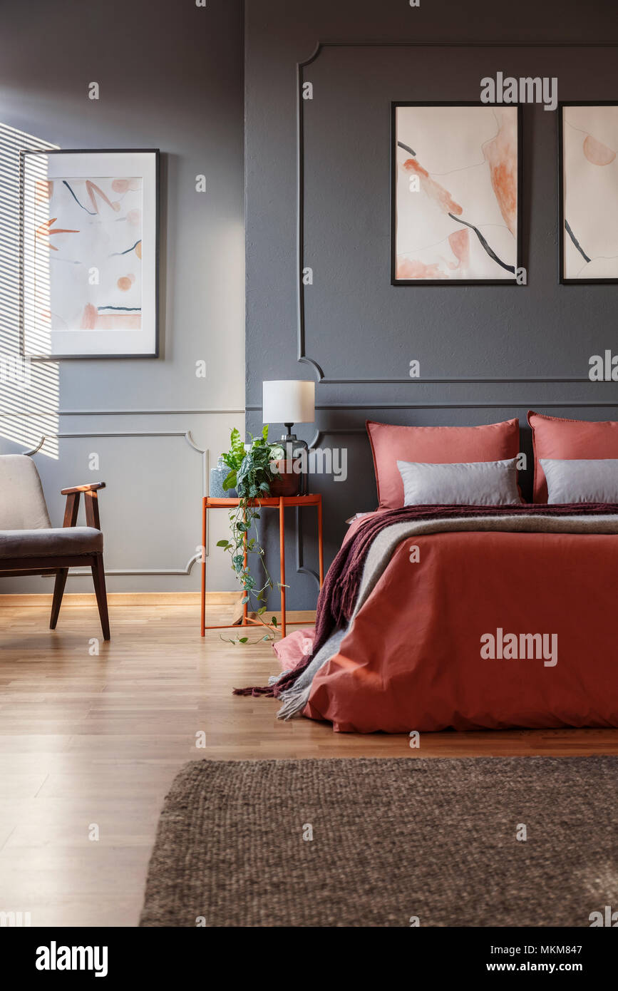 Orange Bed Against Dark Wall With Molding And White Posters Next To A Metal Bedside Table With A Lamp On It In Bedroom Interior Real Photo Stock Photo Alamy