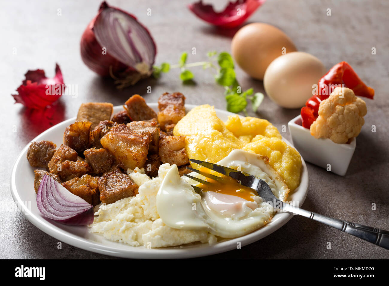 Traditional Romanian food 'Tochitura Moldoveneasca' made with pork meat, egg and cheese with polenta on plate Stock Photo