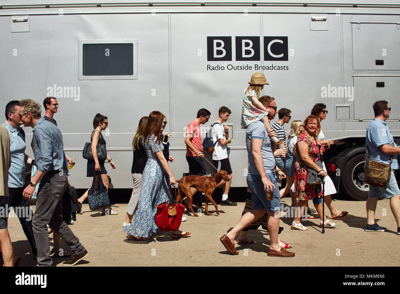People in summer clothing walking past a BBC broadcasting lorry in
