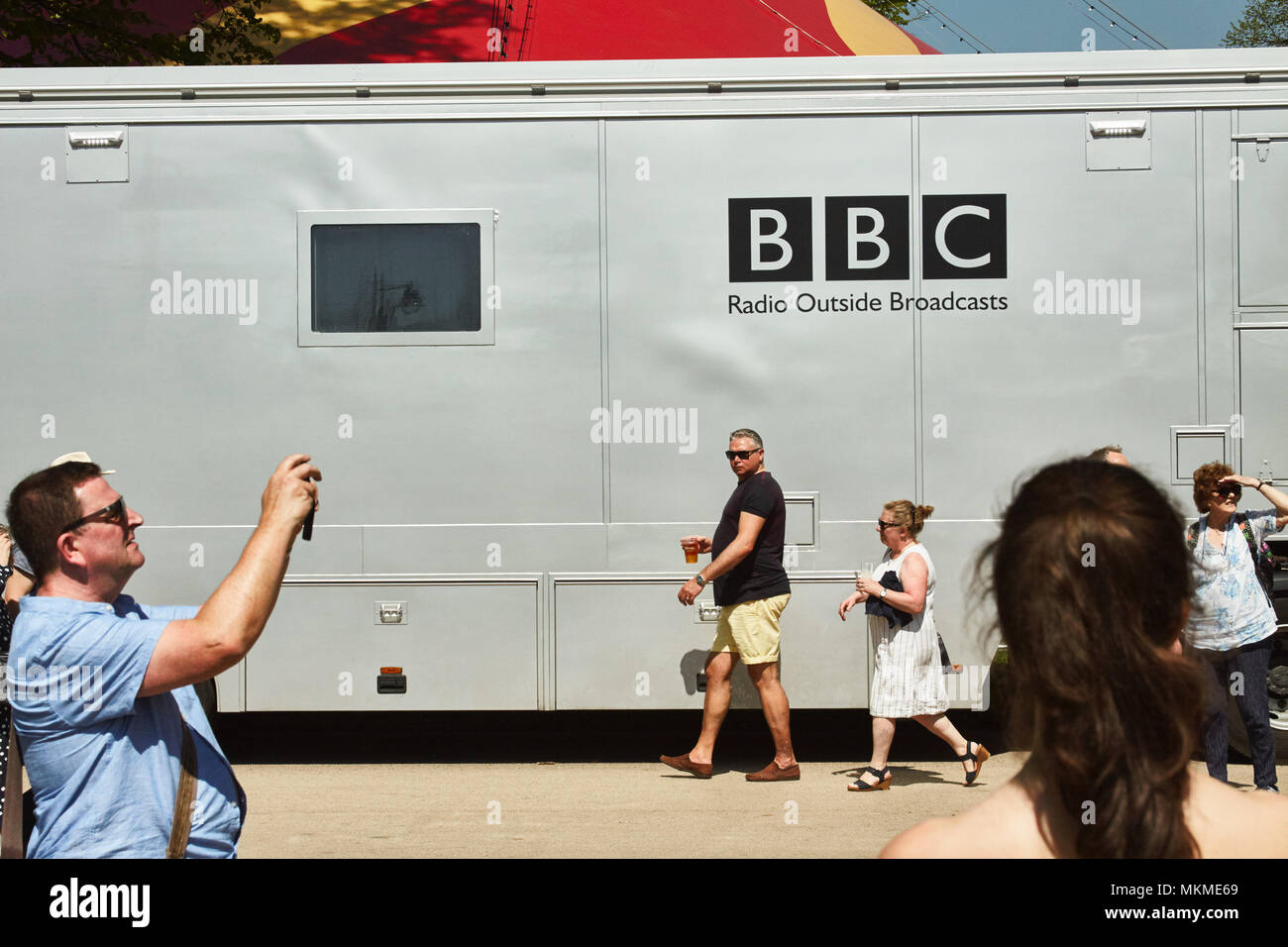 People in summer clothing walking past a BBC broadcasting lorry in