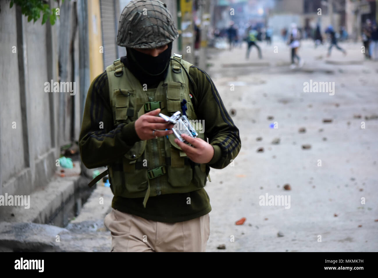 Srinagar, India. 07th May, 2018. An Indian Policeman looks at his broken camera aster it was hit with a stone thrown by a Kashmiri Protester during clashes between people and Indian government forces in Srinagar, Indian Administered Kashmir on 07 may 2015. Hundreds of youth took to the streets and clashes with Government forces against the Killings of 5 Civilians and 5 rebels during a gunfight in Shopian district of the Valley on 06 May 2018. Meanwhile curfew had been put in place to thwart the protests. Credit: Muzamil Mattoo/Pacific Press/Alamy Live News Stock Photo