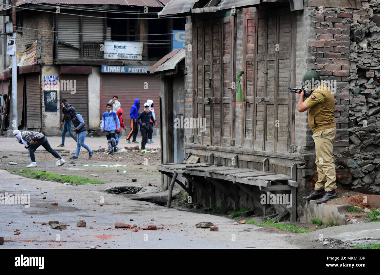 Srinagar, India. 07th May, 2018. An Indian policeman aims at Kashmiri protesters as Youth clash with Indian government forces in Srinagar, Indian Administered Kashmir on 07 may 2015. Hundreds of youth took to the streets and clashes with Government forces against the Killings of 5 Civilians and 5 rebels during a gunfight in Shopian district of the Valley on 06 May 2018. Meanwhile curfew had been put in place to thwart the protests. Credit: Muzamil Mattoo/Pacific Press/Alamy Live News Stock Photo