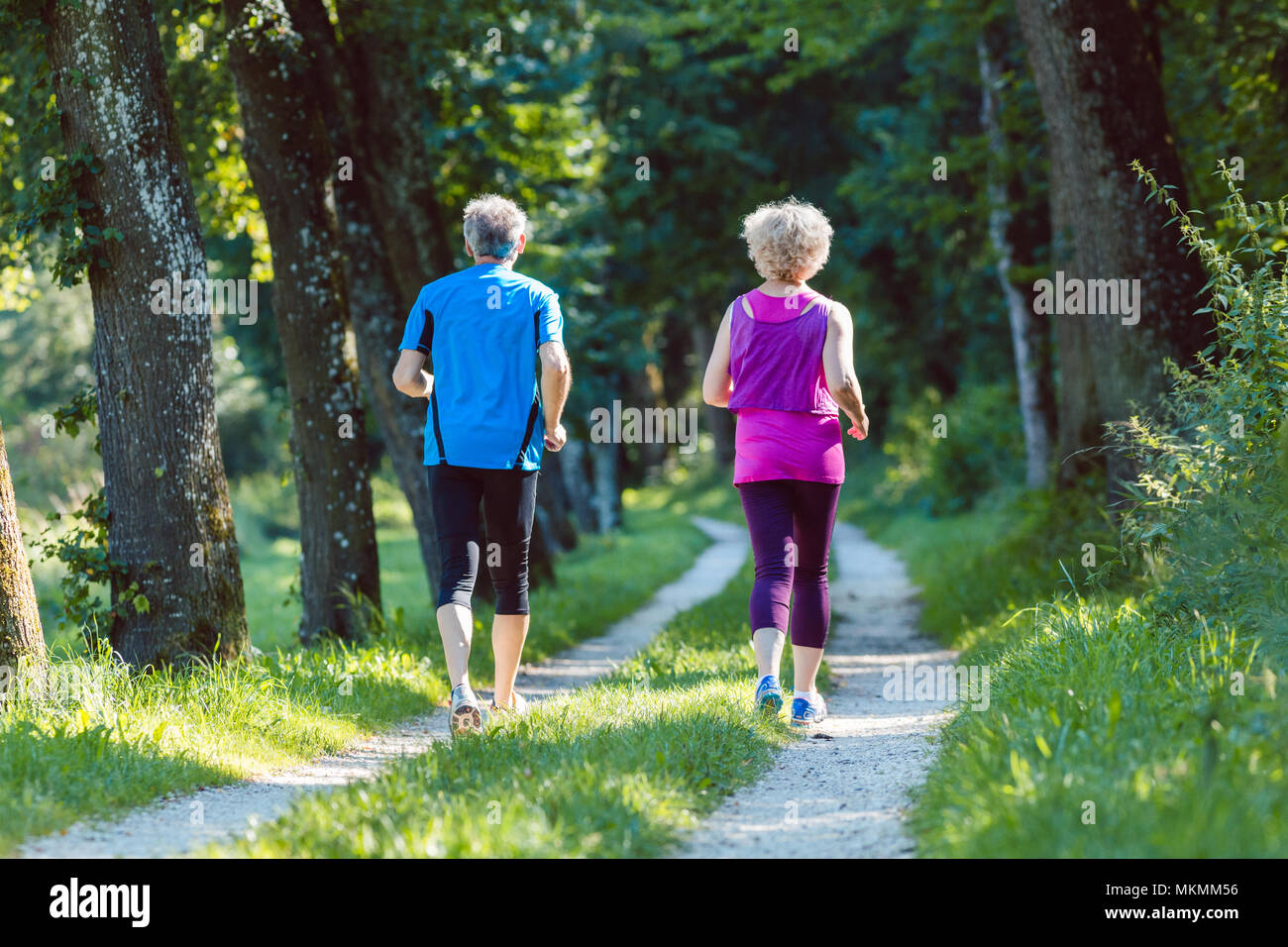 Full length rear view of a senior couple jogging together outdoors Stock Photo