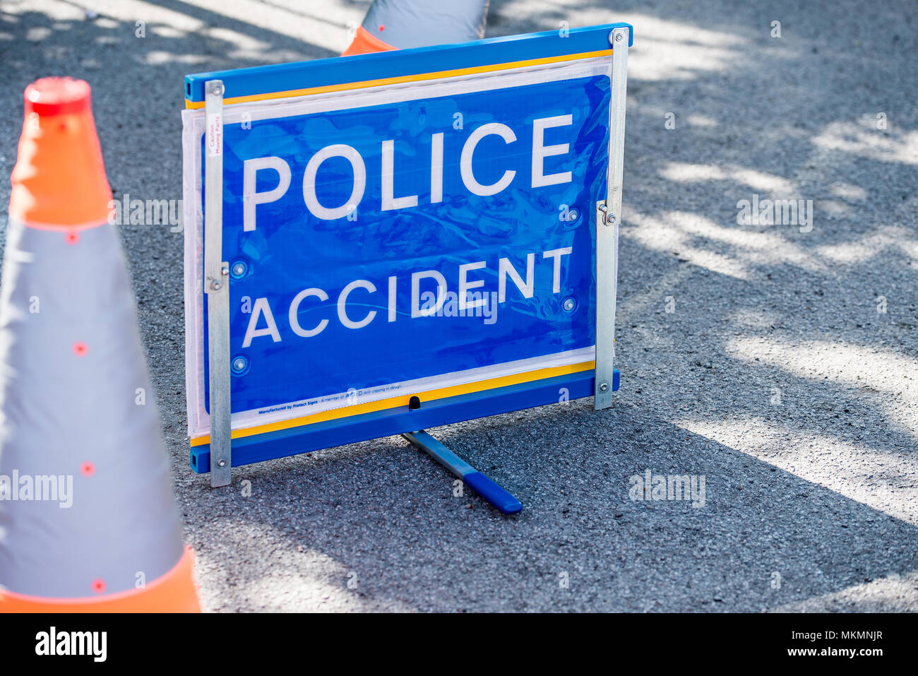 Elevated view of freestanding POLICE ACCIDENT sign by the roadside with two traffic cones Stock