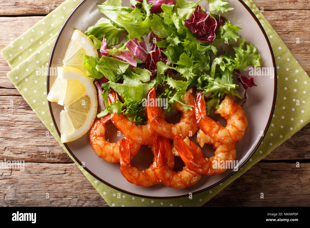 Delicious glazed shrimps with honey and soy sauce and fresh salad closeup on a plate on a table