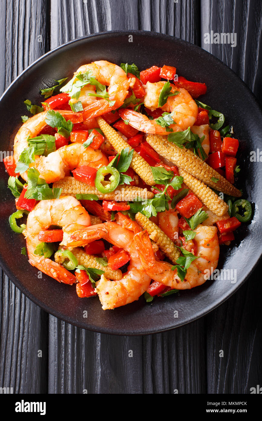 Fried prawns with pepper, garlic, corn cob and herbs closeup on a