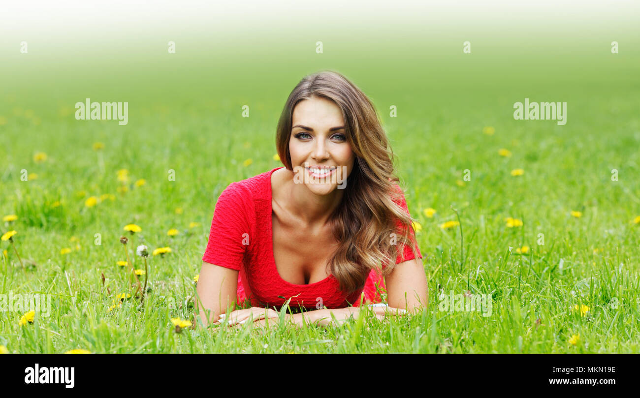 beautiful young woman in red dress lying on grass Stock Photo - Alamy