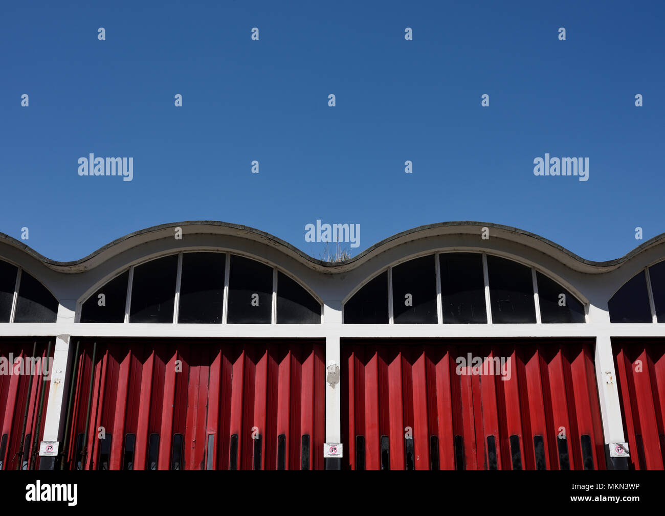 Red concertina folding doors and curvilinear roof on disused fire