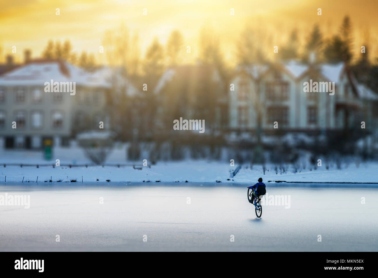 Teenager bike riding on the frozen pond in downtown Reykjavik, Iceland Stock Photo