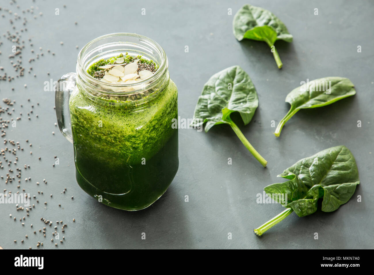 Healthy, green smoothie with spinach and almonds in a jar next to