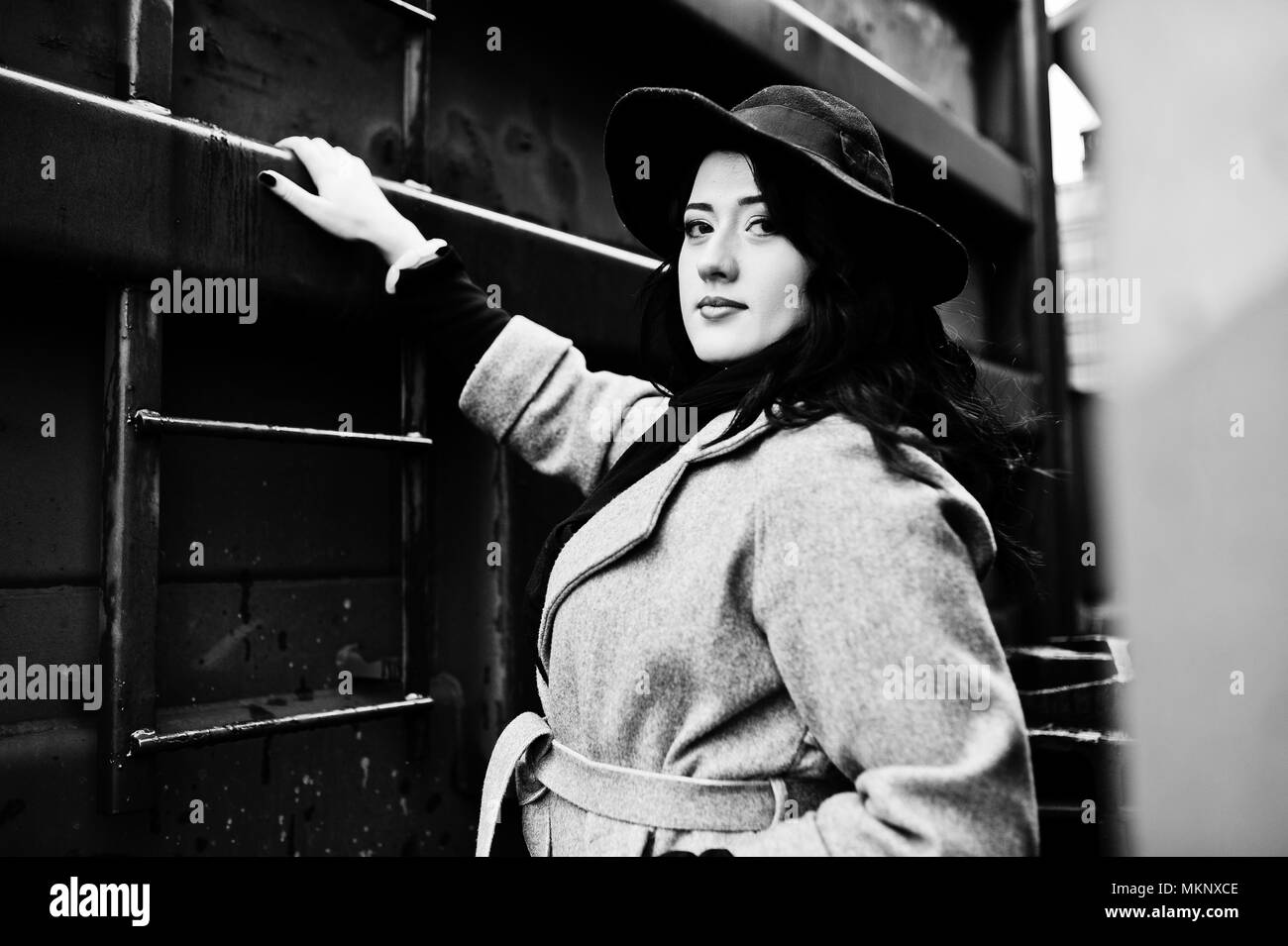 Brunette girl in gray coat with hat in railway station. Stock Photo