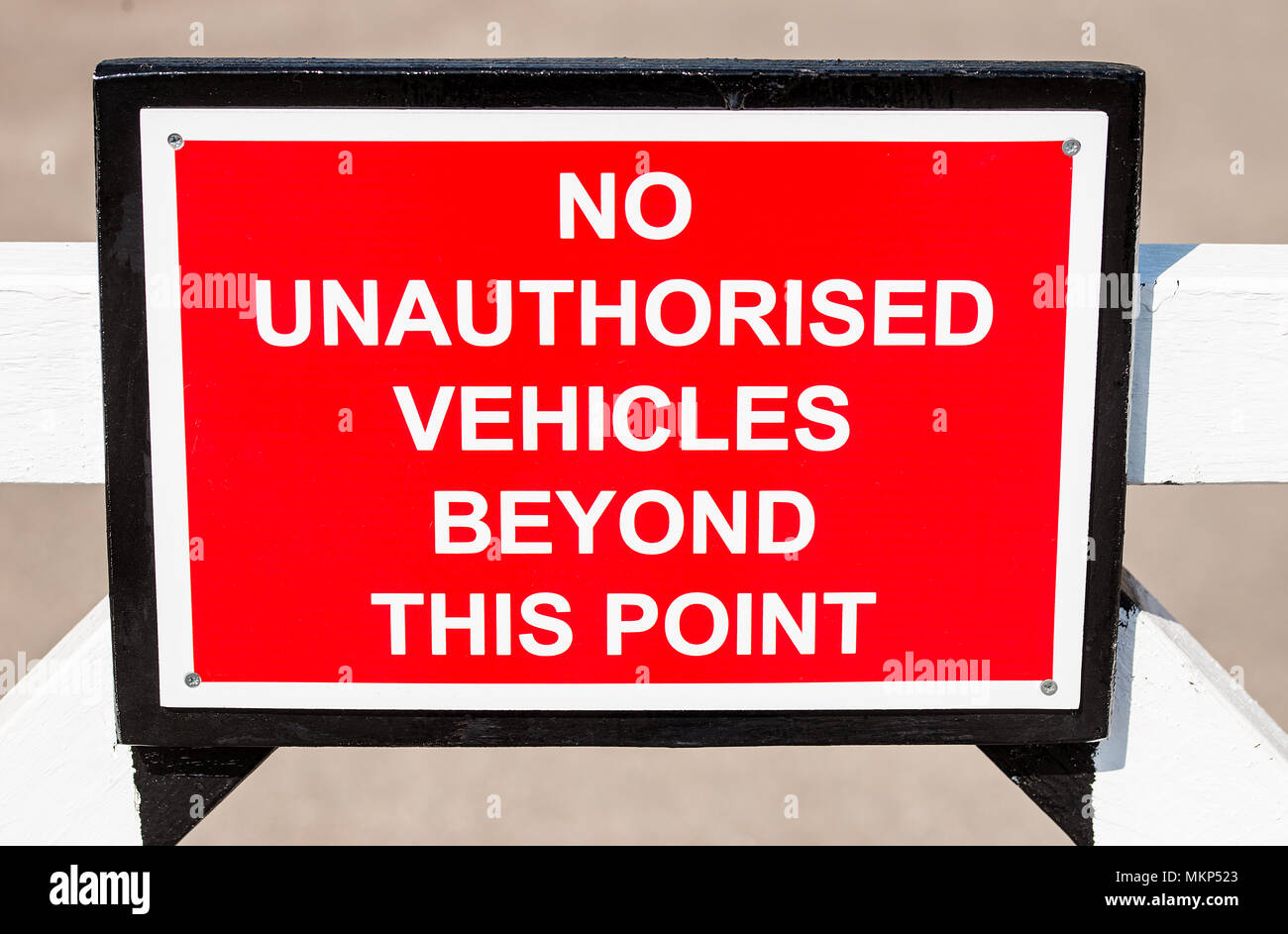 NO UNAUTHORISED VEHICLES BEYOND THIS POINT sign attached to a white gate. Stock Photo