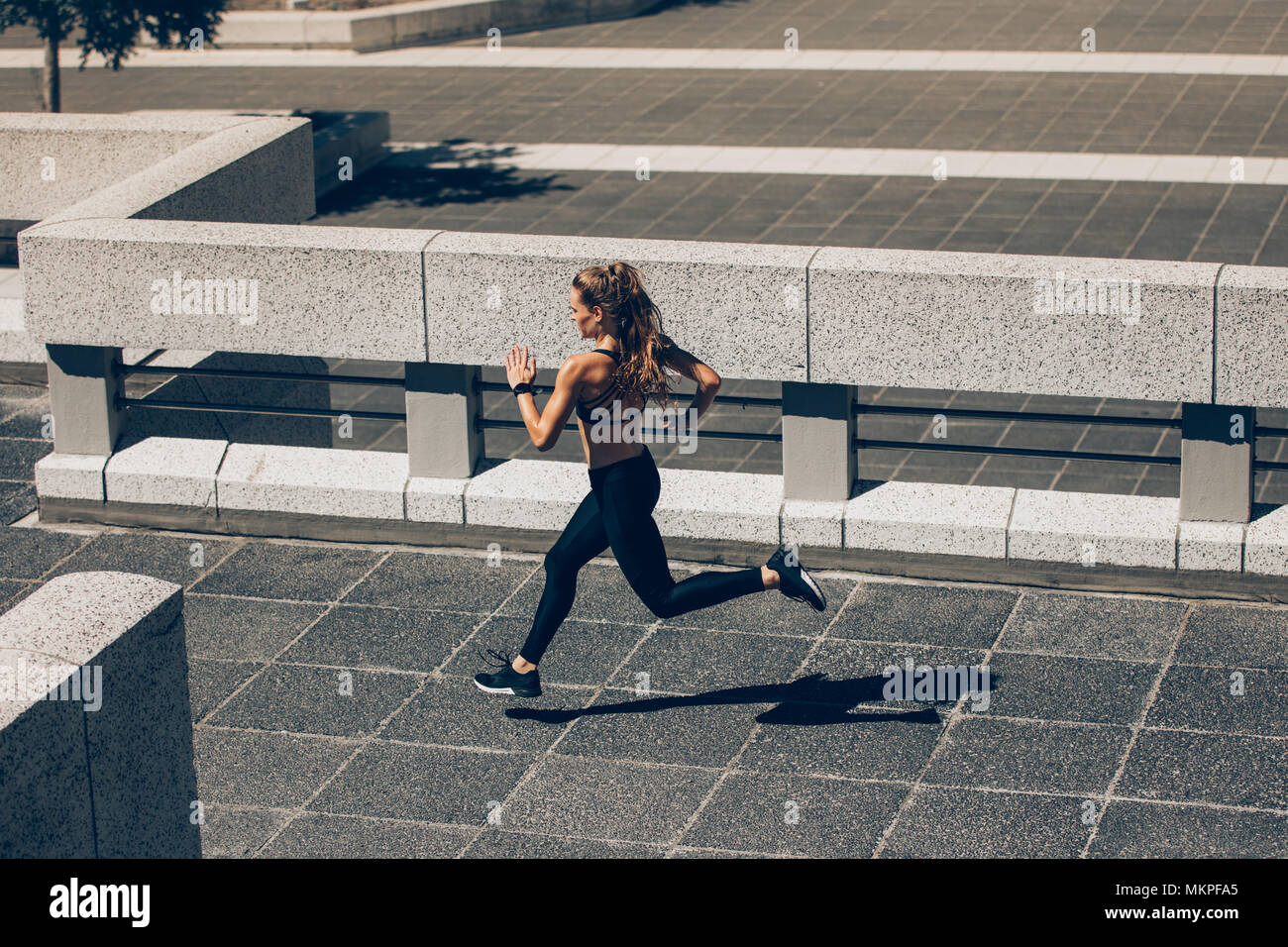 Young woman jogging in city. Female athlete running in the morning. Stock Photo