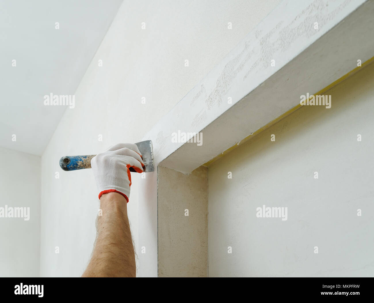 Decorative plaster coating. Man does ragged texture on the wall using a spatula. Stock Photo