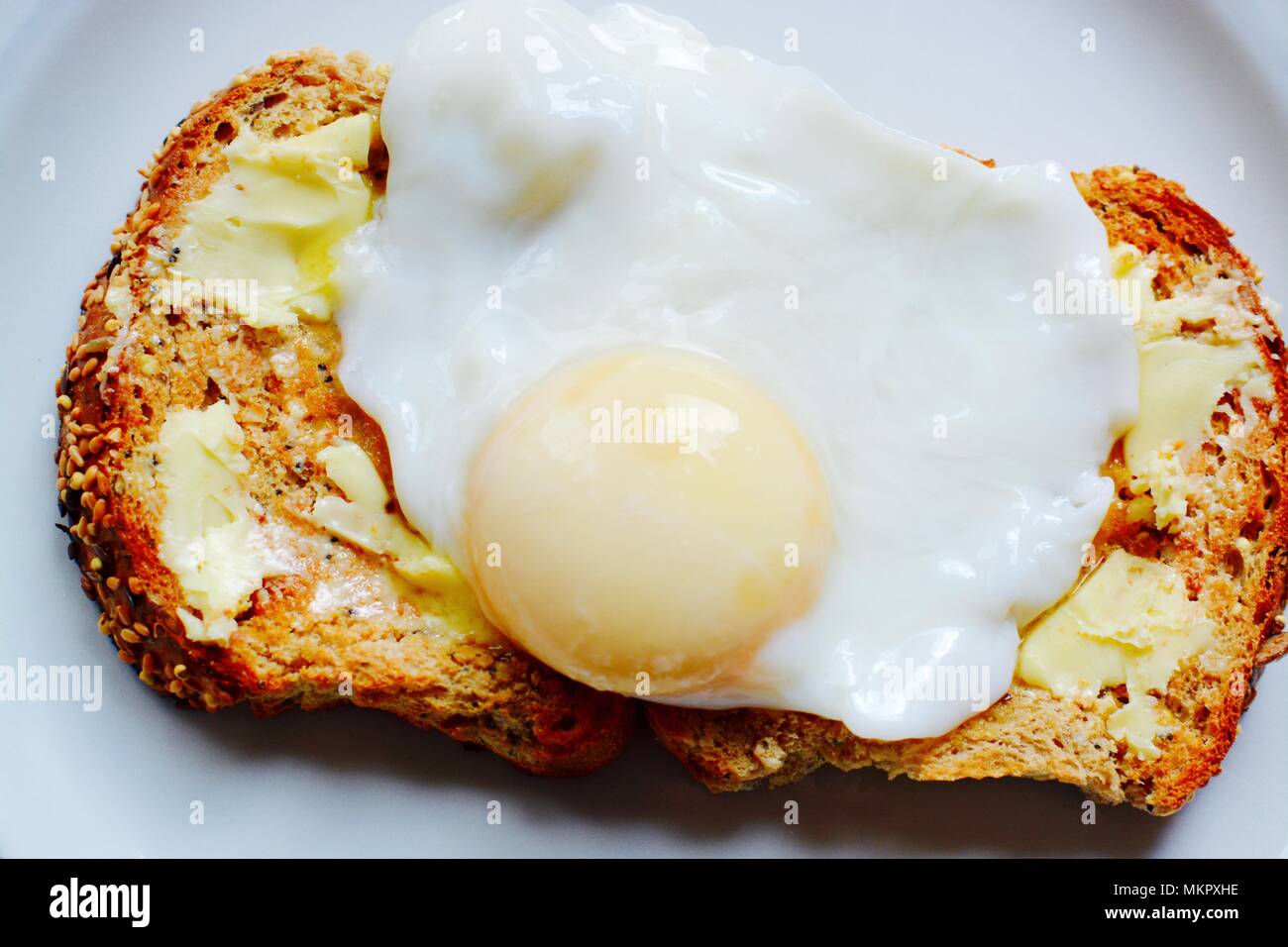 The perfect poached egg on seeded buttered brown toast Stock Photo