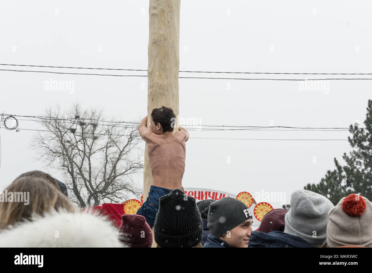 TIRASPOL, MOLDOVA-FEBRUARY 18, 2018: Boy climbing on a wooden pole for the prize. Slavonic folk pagan holiday Maslenitsa (Shrovetide) - a symbolic mee Stock Photo