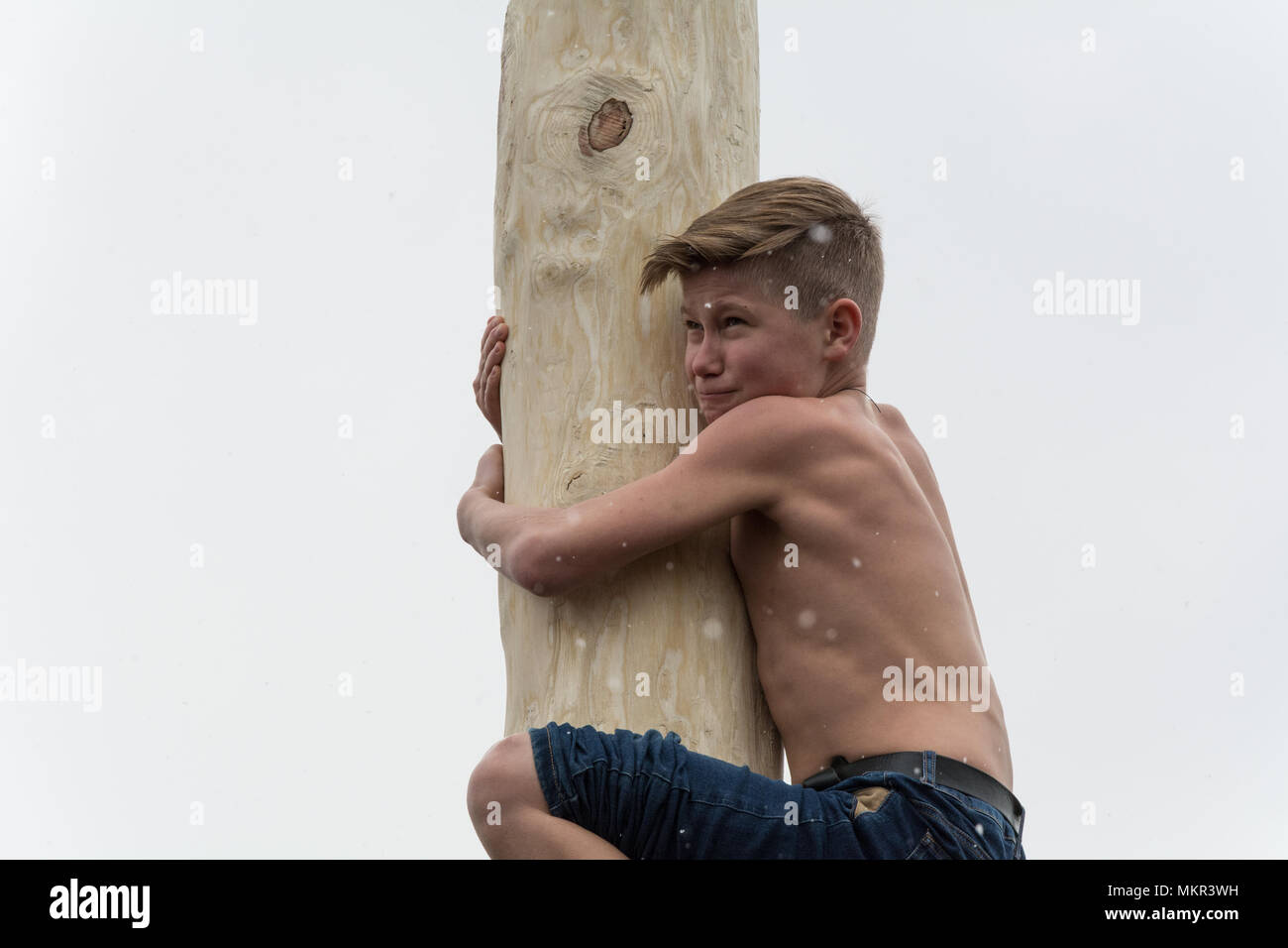 TIRASPOL, MOLDOVA-FEBRUARY 18, 2018: Boy climbing on a wooden pole for the prize. Slavonic folk pagan holiday Maslenitsa (Shrovetide) - a symbolic mee Stock Photo