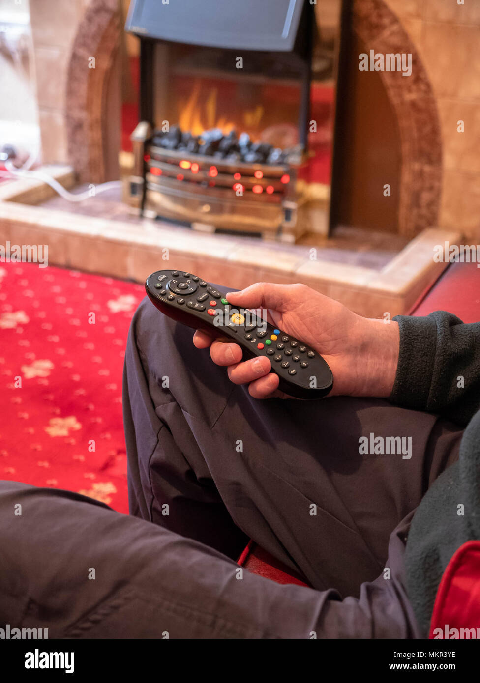 Mature man, living alone, with tv remote control in hand Stock Photo