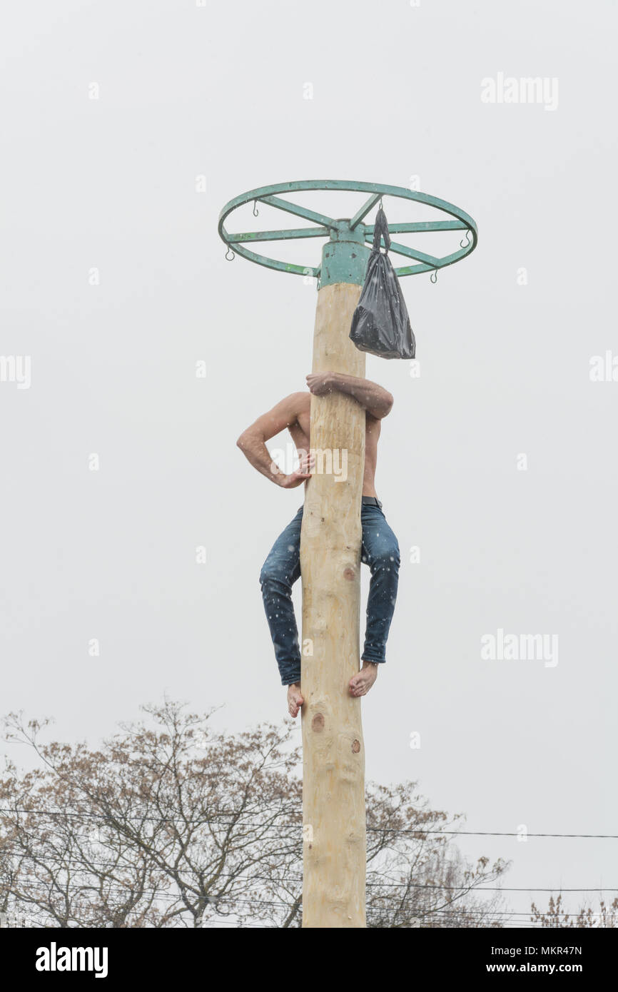 TIRASPOL, MOLDOVA - FEBRUARY 18, 2018: Young man climbing on a wooden pole for the prize. Slavonic folk pagan holiday Maslenitsa (Shrovetide) - a symb Stock Photo
