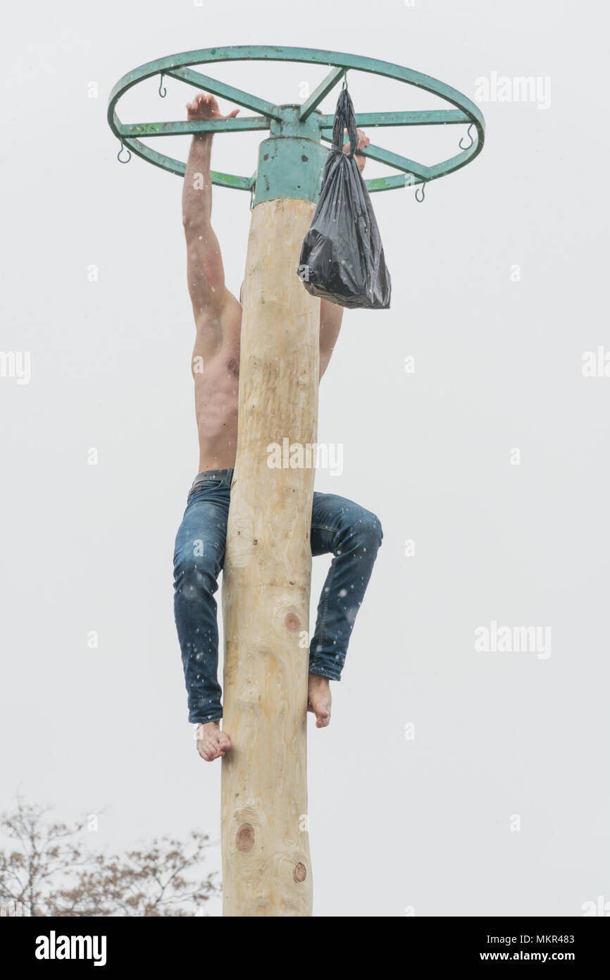 TIRASPOL, MOLDOVA - FEBRUARY 18, 2018: Young man climbing on a wooden pole for the prize. Slavonic folk pagan holiday Maslenitsa (Shrovetide) - a symb Stock Photo
