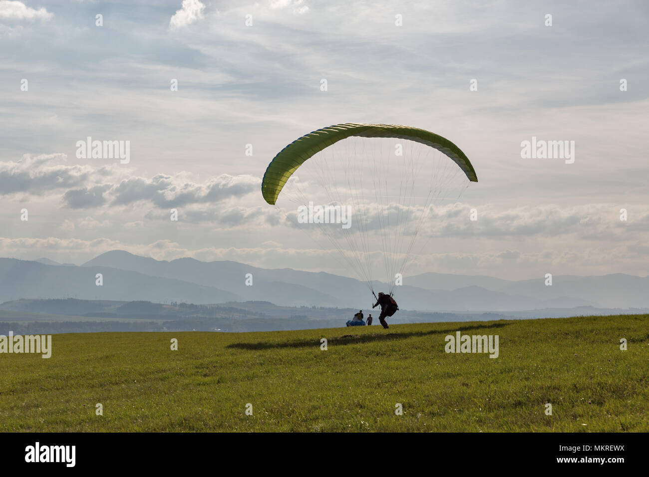 LIPTOVSKY TRNOVEC, SLOVAKIA - SEPTEMBER 30, 2017: Young man paraglider starts flight from the hill close to Tatras mountains. Extreme sports activity. Stock Photo